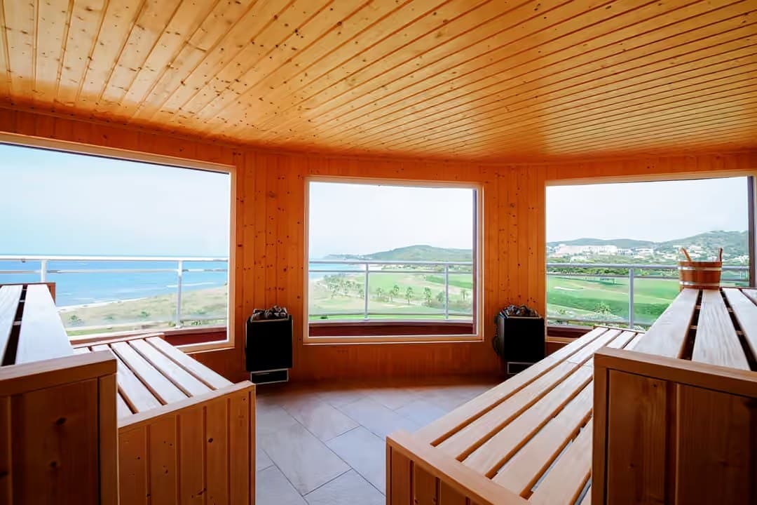 Spa sauna with facing timber benches, twin heaters and panoramic windows over the coast