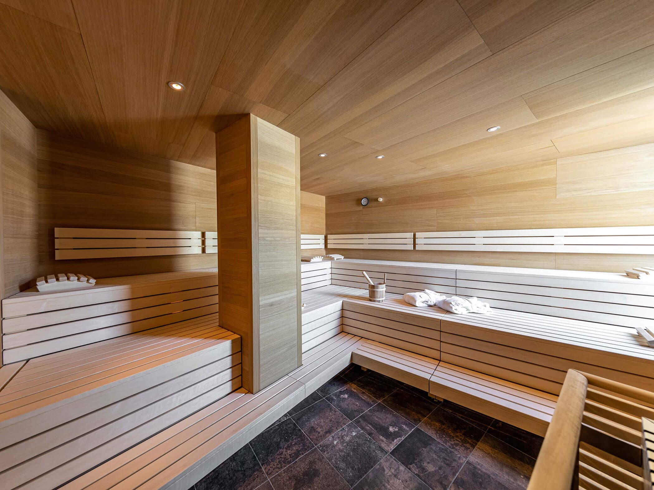 Large spa sauna with tiered pale timber benching and recessed lighting